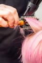 Drying short pink hair of young caucasian woman with a black hairdryer and black round brush by hands of a male Royalty Free Stock Photo