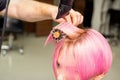 Drying short pink hair of young caucasian woman with a black hairdryer and black round brush by hands of a male Royalty Free Stock Photo