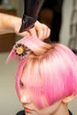 Drying short pink hair of young caucasian woman with a black hairdryer and black round brush by hands of a male Royalty Free Stock Photo