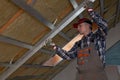 Drywall plaster wall metal fixation. Man holding metal ruler against metal frame on unfinished attic ceiling