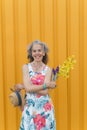 Smiling mature woman with flowers Yellow background Royalty Free Stock Photo