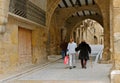 An elderly woman with a cane and her family are walking down the street