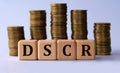 DSCR - acronym on wooden cubes on the background of stacks of coins