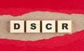 DSCR word on wooden cubes on red torn paper , financial concept background Royalty Free Stock Photo