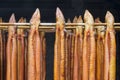 Red brown smoked eels in a row on steel spins in a smokehouse Royalty Free Stock Photo