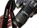 DSLR camera Canon eos 250D with shoulder strap with hand isolated on white background closeup.