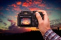 DSLR camera in hand shooting colorful sunset. Photographer shooting POV. Royalty Free Stock Photo