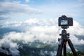 Dslr digital professional camera stand on tripod photographing mountain, Blue sky and cloud landscape. Royalty Free Stock Photo