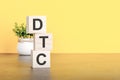 DTC - text on wood cubes stack, yellow background Royalty Free Stock Photo