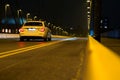 cab driving at night on empty road along yellow street lights