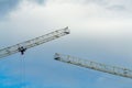 Dual cranes with hanging metal wires and ropes with girder beams in the construction site in urban or industrial area of city Royalty Free Stock Photo