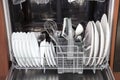 Dual dishwasher with white plates and steel spoons, forks, knifes. Opened door with clear dish Royalty Free Stock Photo