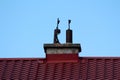 Dual old concrete chimney with two narrow rusted metal pipes on top surrounded with renovated new red roof tiles Royalty Free Stock Photo