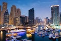 Dubai marina with boats and buildings with gates at night with lights