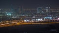 Dubai skyline with villa houses and construction site of new towers on a background aerial night timelapse.