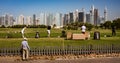 Golfers practice on driving range with Dubai skyline in the back