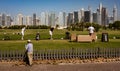 Golfers practice on driving range with Dubai skyline in the back