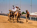 Men ride camels with others nearby to train for racing in close