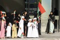 womens and children in traditional clothes wave flags of the United Arab Emirates.