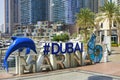 Dubai, UAE, Sep 2022. Modern colorful art installation hashtag Dubai Marina logo on Marina walk promenade.