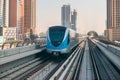 Dubai, United Arab Emirates - November 06, 2021: Dubai metro train on rails at background of skyscrapers. Famous outdoor subway Royalty Free Stock Photo