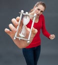 Dubious beautiful young woman holding an hour glass against stress