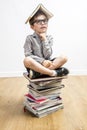 Dubious schoolboy with smart eyeglasses with book on his head Royalty Free Stock Photo