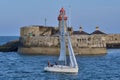 Beautiful creative evening view of sailboat passing in front of red East Pier lighthouse in Dun Laoghaire harbor