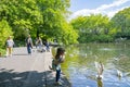 People walking leisurely towards around lake in public park of St. Stephens Green in city