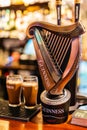 Selective focus on Guinness tap with blurred pints of foamy beer