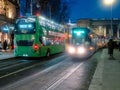 Dublin, Ireland - 20.12.2022: Busy traffic in the capital with double decker bus and Luas city tram in motion after dusk