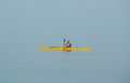 Dublin, Ireland - 07.22.2021: Man with bright yellow canoe rowing in the mist on calm sea water, sunrise. An enthusiast canoeing o Royalty Free Stock Photo