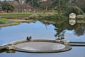 Reflective view of circular bridge over pond in Blackrock Park. Couple of children and