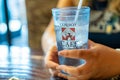 Female hand holds a drinking water glass with the Cowboy Cafe logo while eating inside the