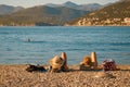 Dubrovnik, Croatia - October 12, 2019: Two young women are laying at the pebble beach with panorama of mountains