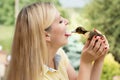 A young woman kisses little duck.Duck plucks the girl tongue.