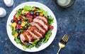 Duck salad with grilled breast with red orange, kumquat, blueberry and chard, frisse, mizuna and arugula leaves on blue table Royalty Free Stock Photo