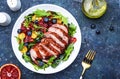 Duck salad with grilled breast with red orange, kumquat, blueberry and chard, frisse, mizuna and arugula leaves on blue table Royalty Free Stock Photo