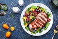 Duck salad with grilled breast with red orange, kumquat, blueberry and chard, frisse, mizuna and arugula leaves on blue table