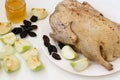 Duck in spices is located on a white plate with apples and prunes