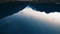 Ducks swim on a mirrored smooth mountain lake