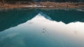 Ducks swim on a mirrored smooth mountain lake