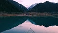 Ducks swim on a mirrored smooth mountain lake