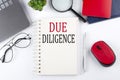 DUE DILIGENCE text on a notepad with laptop on the white background
