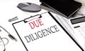 DUE DILIGENCE text on paper clipboard with chart and notebook on withe background