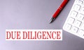 DUE DILIGENCE text written on a gray background with pen and calculator