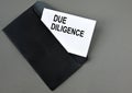 DUE DILIGENCE - words on white paper on a black envelope with a magnifying glass Royalty Free Stock Photo