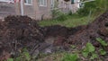 Dug dirty pit in ront of the house with grass behind. Clip. Repair works of city communications.