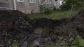 Dug dirty pit in ront of the house with grass behind. Clip. Repair works of city communications.