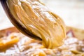 Dulce de leche or homemade caramel dripping from wooden spoon, macro photo of food